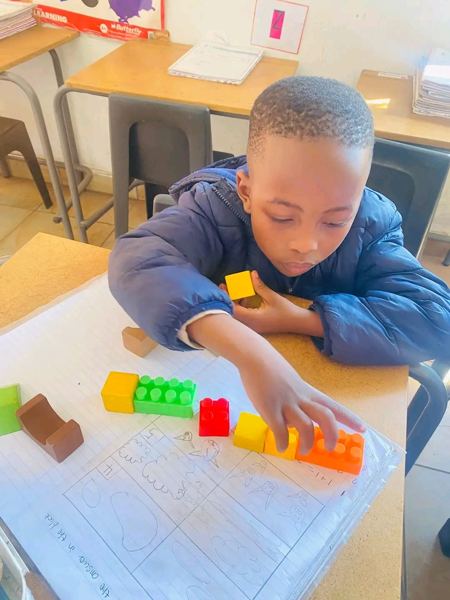 A learner lining up building blocks to work out a sum